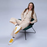 Woman sitting on chair wearing Diawin yellow shoes for wide and diabetic feet.