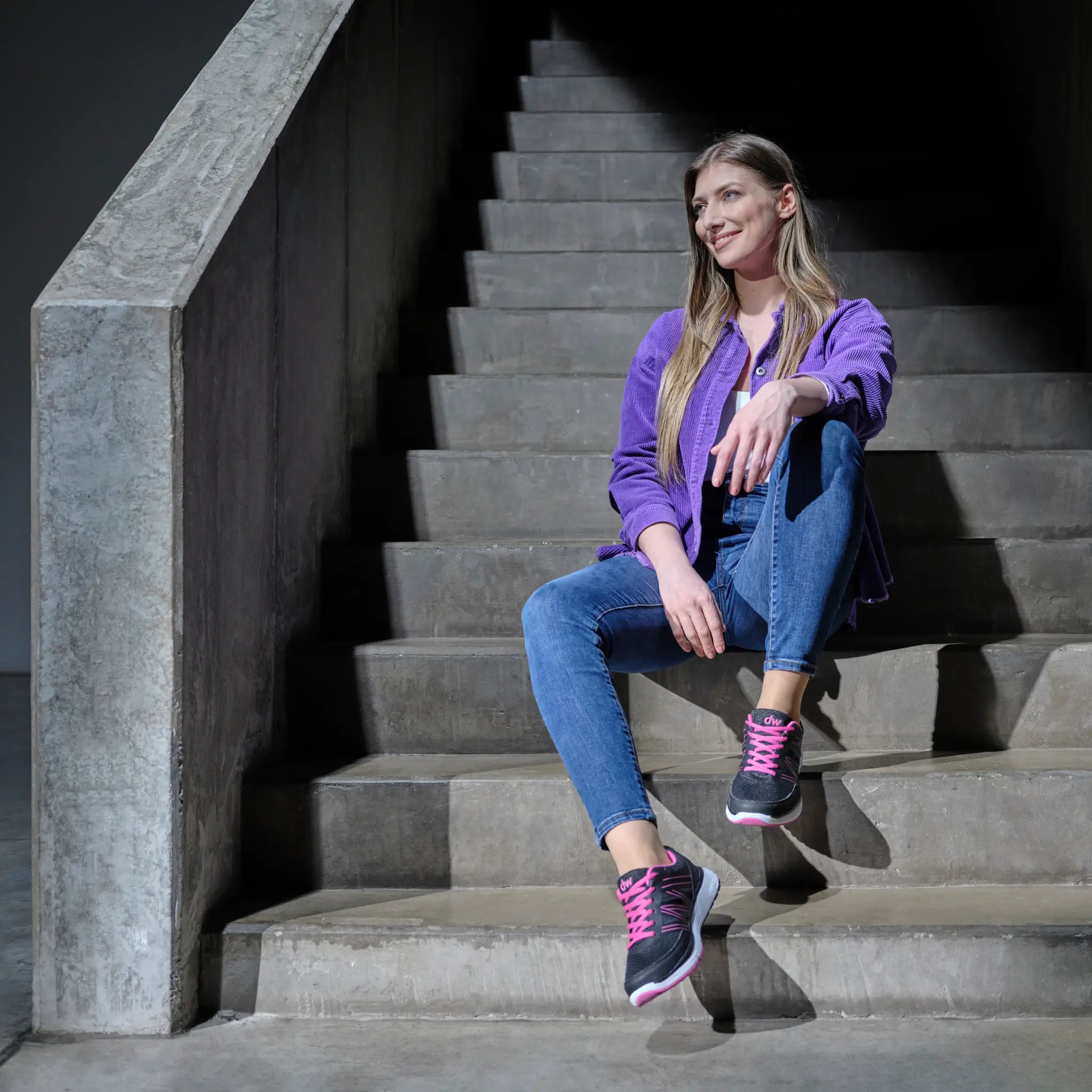 Woman wearing Diawin black sneakers for wide and diabetic feet sitting on stairs.